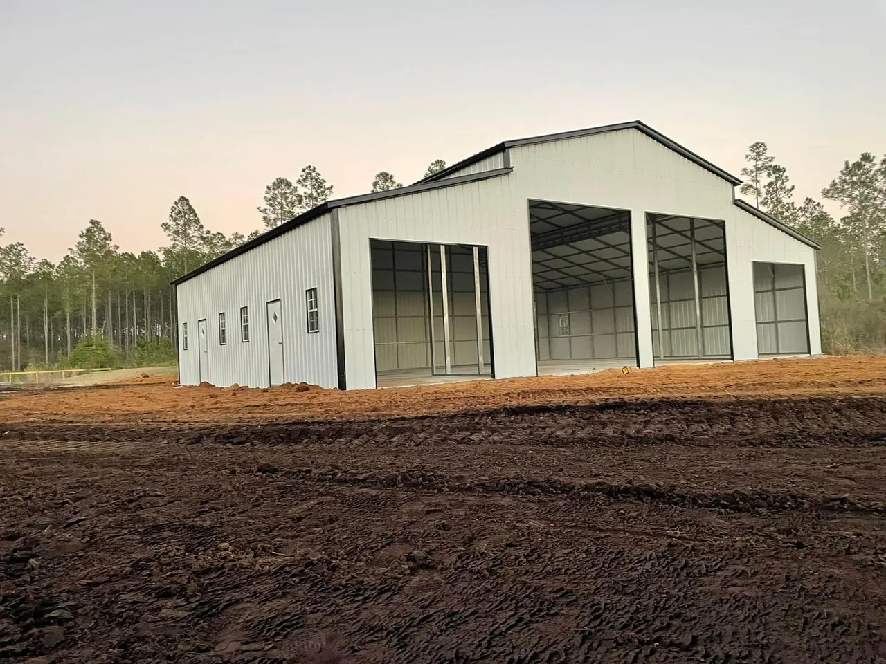 Large white barn-style steel building with open center and side bays